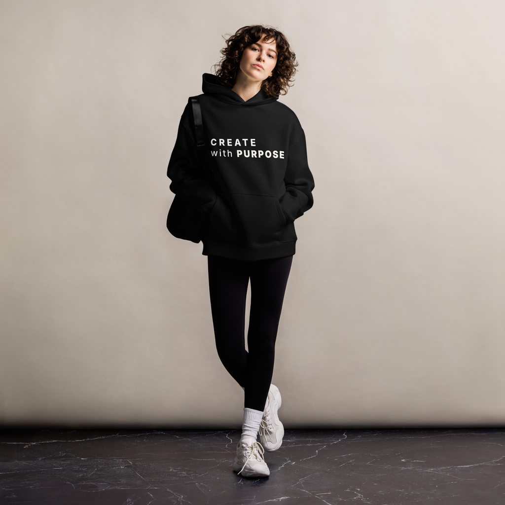 Black oversized hoodie worn by woman, relaxed streetwear fit with “CREATE with PURPOSE” print
