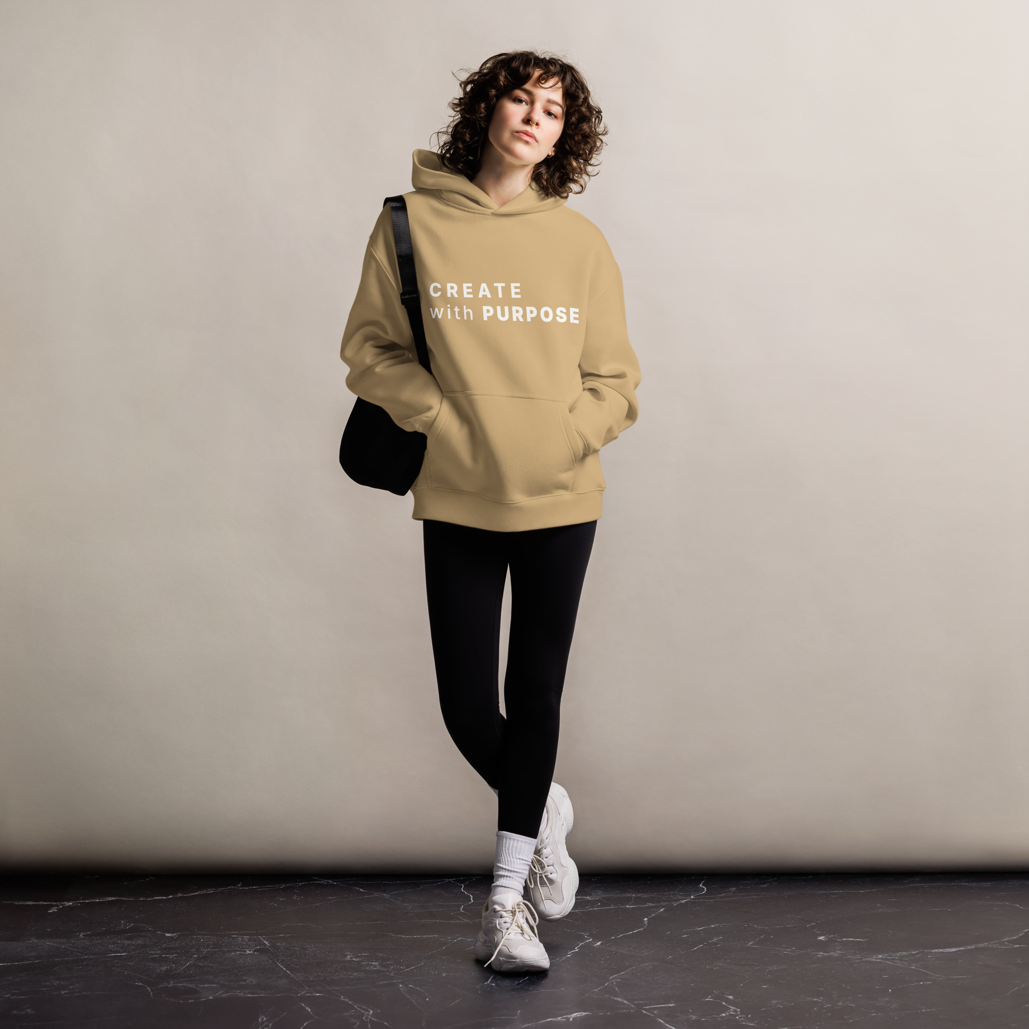 Sand oversized hoodie worn by woman, relaxed streetwear fit with “CREATE with PURPOSE” print