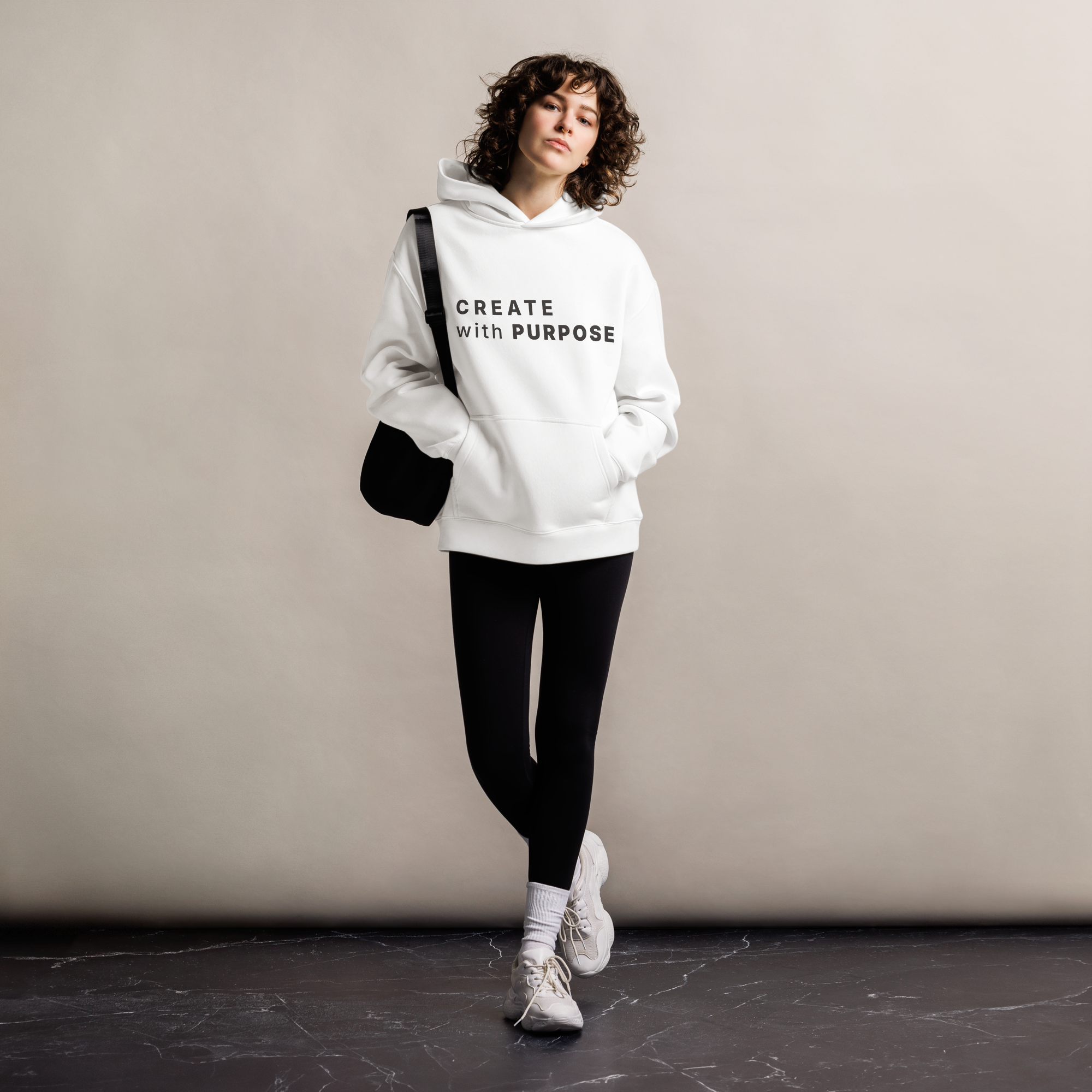 White oversized hoodie worn by woman, relaxed streetwear fit with “CREATE with PURPOSE” print